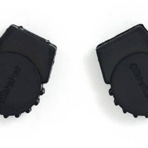 A pair of black plastic bottle caps on a white surface.