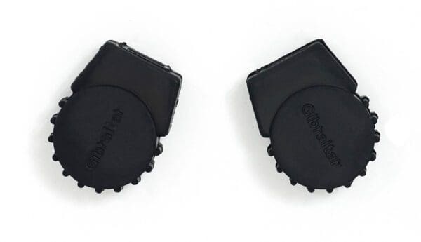 A pair of black plastic bottle caps on a white surface.