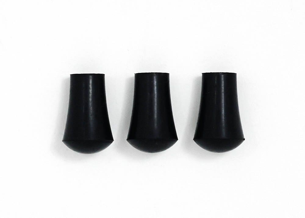 Three black plastic plugs on a white surface.