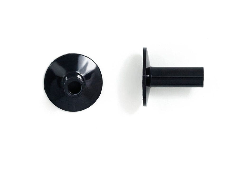 A pair of black plastic knobs on a white surface.