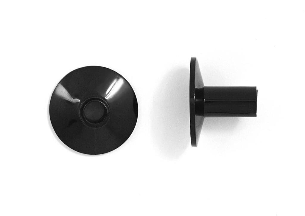 A pair of black plastic knobs on a white surface.